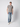 A young man stands against a plain light background, wearing the PROJEK RAW Mens Liquid Cotton Short Sleeve T-shirt in grey, paired with light blue jeans and white sneakers. He faces forward with a relaxed posture and neutral expression.