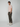 A young man with short curly hair and a neutral expression wears a light pink T-shirt, PROJEK RAW MENS CARGO PULL-ON JOGGER pants with cargo pockets, and white sneakers. He stands slightly sideways against a plain light gray background.