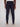 A person faces away from the camera, wearing Projek Raw’s ANTOINE-NAVY jogger pants with an elastic waistband, side pockets, and one back pocket, paired with a white shirt and gray sneakers.