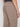 A person wearing Projek Raw ANTOINE-BEIGE pants featuring an elastic waistband and a back welt pocket, viewed from behind and shown from the waist down.
