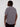 A person with short dreadlocks stands facing away from the camera, wearing the Projek Raw ALEXANDER-GREY short-sleeve 4-way stretch shirt and dark pants against a plain light background.