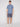 A man faces forward against a plain background wearing the Projek Raw ARNAUD-BLUE 4-way stretch shirt, dark blue shorts, and white sneakers, displaying a modern look with a neutral expression.