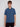 A young man with straight light brown hair wears the Projek Raw ADRIAN-BLUE short-sleeved, button-up travel shirt made from easy-to-pack fabric and dark pants. He faces forward with a neutral expression against a light-gray background.