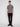 A young man with straight light brown hair and a neutral expression wears the Projek Raw ADRIAN-GREY short-sleeve 4-way stretch shirt with a zippered chest pocket, paired with black pants and sneakers against a plain white background.