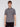 A person with light brown hair wears Projek Raws ADRIAN-GREY short-sleeve button-up shirt with a zippered chest pocket and black pants, standing against a plain white background and looking directly at the camera.