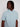 A person with medium-length dreadlocks wears the Projek Raw BLAISE-AQUA mens shirt—light blue, short-sleeve, collared, with subtle white stripes and two chest pockets—looking to the side against a plain background.