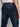 A person is shown from the back wearing Projek Raws KEVIN-INK BLUE slim fit jeans and a white shirt, highlighting the indigo-black denim’s back pockets, waistband, and black leather brand patch.