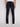 Someone wearing Projek Raw HENRI-BLUE BLACK RINSE jeans and white sneakers stands with their back to the camera, highlighting the rear view of the jeans against a simple, light background.