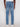 A person wearing Projek Raw WYATT-INDIGO WASH jeans and white sneakers stands facing away from the camera, displaying the back and pockets of the jeans against a plain white background.