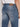 A person wearing Projek Raw’s XANDER-DISTRESSED INDIGO regular fit jeans with prominent back pockets and a brown leather waistband patch, shown from the waist down and viewed from behind.
