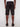 A man stands with his back to the camera, wearing Projek Raws EDGAR-BLACK knee-length shorts featuring back pockets, paired with a white shirt and black shoes against a plain light background.