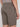A model showcases the Projek Raw ANTHONY-MOSS taupe shorts, featuring side pockets and a back welt pocket, viewed from behind against a plain background.