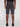 A person faces away from the camera, wearing Projek Raw NATHANIAL-DARK CHARCOAL knee-length shorts, a black shirt, and black shoes against a plain light gray background.