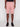 Wearing Projek Raws NATHANIAL-ROSE light pink, knee-length, multi-pocket shorts and black sneakers, a person stands against a white background with relaxed hands at their sides.