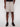 A person is shown from mid-torso to feet, standing against a plain white background and wearing Projek Raw CYPRIAN-MUSHROOM light beige drawstring shorts, a black shirt, and black sneakers.