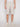 A person wearing Projek Raw DARIAN-NATURAL light beige knee-length shorts, a white tucked-in shirt, and white sneakers stands against a plain white background. The image is cropped at the shoulders.