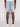 A person is seen from the back in Projek Raw’s JOVIAN-BLEACH light blue denim shorts with rolled cuffs, decorative-stitched back pockets, a brown patch detail, paired with white sneakers and a white top.