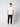 A young man stands against a gray background, wearing PROJEK RAW Men’s Stretch Bungee Cargo Jogger in black, a white short-sleeve t-shirt, and white sneakers. He looks forward with a neutral expression, arms relaxed at his sides.