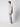 A young man with curly hair stands in profile against a plain light background, wearing PROJEK RAW’s Men’s Bungee Loose Pant made from stretch fabric, a light grey jacket, and white sneakers—ideal for casual everyday wear.