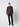 A young man stands against a plain light background, wearing a PROJEK RAW Mens Long Sleeve Casual Dress Shirt in brown with front pockets, black pants, and black shoes. He faces forward with a neutral expression.