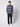A man stands facing forward against a plain backdrop wearing the PROJEK RAW Mens Long Sleeve Plaid Button-up Shirt, dark pants, and white sneakers. One hand in his pocket highlights this casual wardrobe essential.