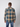 A man faces away from the camera, wearing a PROJEK RAW Mens Long Sleeve Plaid Button-up Shirt in tan, blue, and black with blue jeans against a plain light background.