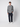 A young man stands against a light gray background, wearing the PROJEK RAW Mens Long Sleeve Plaid Button-up Shirt in blue and gray, paired with dark navy pants and white sneakers. He faces forward with a neutral expression.