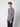 A young man with curly brown hair models the PROJEK RAW Mens Long Sleeve Plaid Button-up Shirt in blue and white, paired with navy pants, standing against a plain light gray background and gazing slightly to the side.