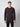 A young man with short light brown hair wears a black PROJEK RAW Mens Long Sleeve Henley Top and black pants, standing against a plain light gray background, facing the camera with a neutral expression.