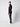 A young man stands in profile against a plain light background, wearing a black zip-up jacket, white sneakers, and PROJEK RAW Men’s Brushed Bungee 5-Pocket Pants.