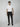 A young man faces forward against a gray background, wearing a white t-shirt, black slip-on shoes, and the PROJEK RAW Mens Solid Bungee Relaxed Chino Pant featuring a bungee waistband.