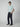 A young man stands against a plain background, wearing a light blue short-sleeve t-shirt and PROJEK RAW Mens Bungee Loose Cargo Pant with side pockets, paired with navy slip-on shoes. He faces slightly to the side with one hand in his pocket.