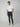 A man poses against a plain background wearing a white t-shirt, beige slip-on shoes, and PROJEK RAW Mens Bungee Chino Pant, one hand in his pocket, showcasing versatile casual style with a neutral expression.