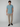 A man stands facing forward against a plain background, wearing a light blue PROJEK RAW Mens Short Sleeve Crew Neck T-shirt, beige pants, and black slip-on shoes for a relaxed casual look.