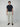 A man faces forward against a plain background, wearing a dark navy t-shirt, brown loafers, and light beige PROJEK RAW Mens Textured Bungee Melange Chino Pant made from stretch fabric, with his arms relaxed by his sides.