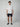A young man stands facing forward, wearing a PROJEK RAW Mens Short Sleeve Shirt with Floral Print, dark navy shorts, and navy slip-on shoes against a plain light gray background.