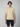 A young man with brown hair stands against a plain background, wearing a light yellow PROJEK RAW Mens Short Sleeve Knit Polo Sweater with white trim and navy shorts, facing forward with a neutral expression.