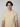 A young man with medium-length brown hair wears a PROJEK RAW Mens Short Sleeve Knit Polo Sweater in light beige with subtle vertical stripes, standing against a plain light background.