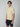 A young man with brown hair wears a PROJEK RAW Mens Short Sleeve Knit Polo Sweater with a pocket and dark navy shorts, standing against a plain light gray background.