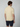 A man faces away from the camera, wearing a light yellow PROJEK RAW Mens Short Sleeve Knit Polo Sweater and navy blue shorts, set against a plain light gray background.