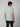 A young man with brown hair faces away, wearing a light mint green PROJEK RAW Mens Short Sleeve Crew Neck T-shirt and black pants, perfect for any casual wardrobe, set against a plain light gray background.