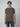 A young person with short brown hair wears the PROJEK RAW Mens Short Sleeve Carbon Peached Pigment Wash Jersey T-shirt in olive green and blue jeans, standing forward against a light gray background for a relaxed vintage vibe.