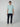 A young man stands against a plain background, wearing a PROJEK RAW Mens Short Sleeve Carbon Peached Pigment Wash Jersey T-shirt in light blue, dark navy cargo pants, and white sneakers, facing forward with a neutral expression.
