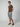 A man stands with hands in pockets, wearing a brown t-shirt, PROJEK RAW MENS CARGO SHORT in light gray, and brown slip-on shoes, ready for any outdoor adventure against a plain light gray background.