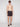 A man stands shirtless and facing forward against a plain light background, wearing Projek Raw BRYSON-CHARCOAL black swim shorts with a green drawstring, black sunglasses, and black slide sandals.
