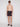 A man wears Projek Raw’s BRUNO-CHARCOAL swim shorts, black slide sandals, and sunglasses. He stands shirtless, facing forward with a neutral expression against a plain white background.