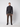 A young man stands facing forward against a plain light background, wearing a dark quarter-zip sweater, PROJEK RAW Mens Stretch Bungee Cargo Pant in olive brown, and black sneakers. His arms are relaxed at his sides.
