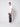 A young man stands sideways, looking at the camera, wearing a plain white t-shirt, PROJEK RAW Men’s Stretch Bungee Cargo Jogger, and white sneakers against a plain light gray background.