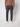 A person faces away, wearing PROJEK RAW Men’s Textured Bungee Pull-on Chino Pant in dark gray, paired with a brown long-sleeve top and white shoes against a plain light background.