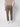 A man faces away, wearing PROJEK RAW Men’s Canvas Bungee Pull-on Cargo Jogger with flap pockets, elastic cuffs and waistband, paired with white sneakers. The background is plain and light-colored.